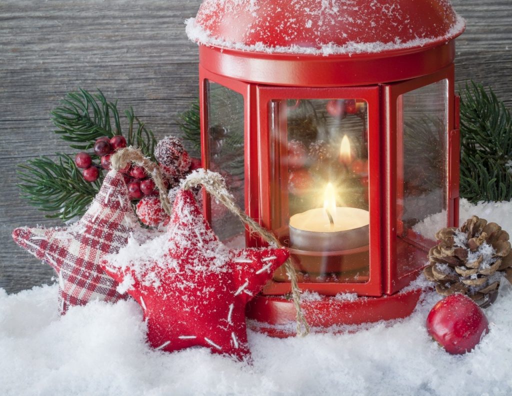 a person wearing a red dress and holding a candle in a red box with a candle and pine