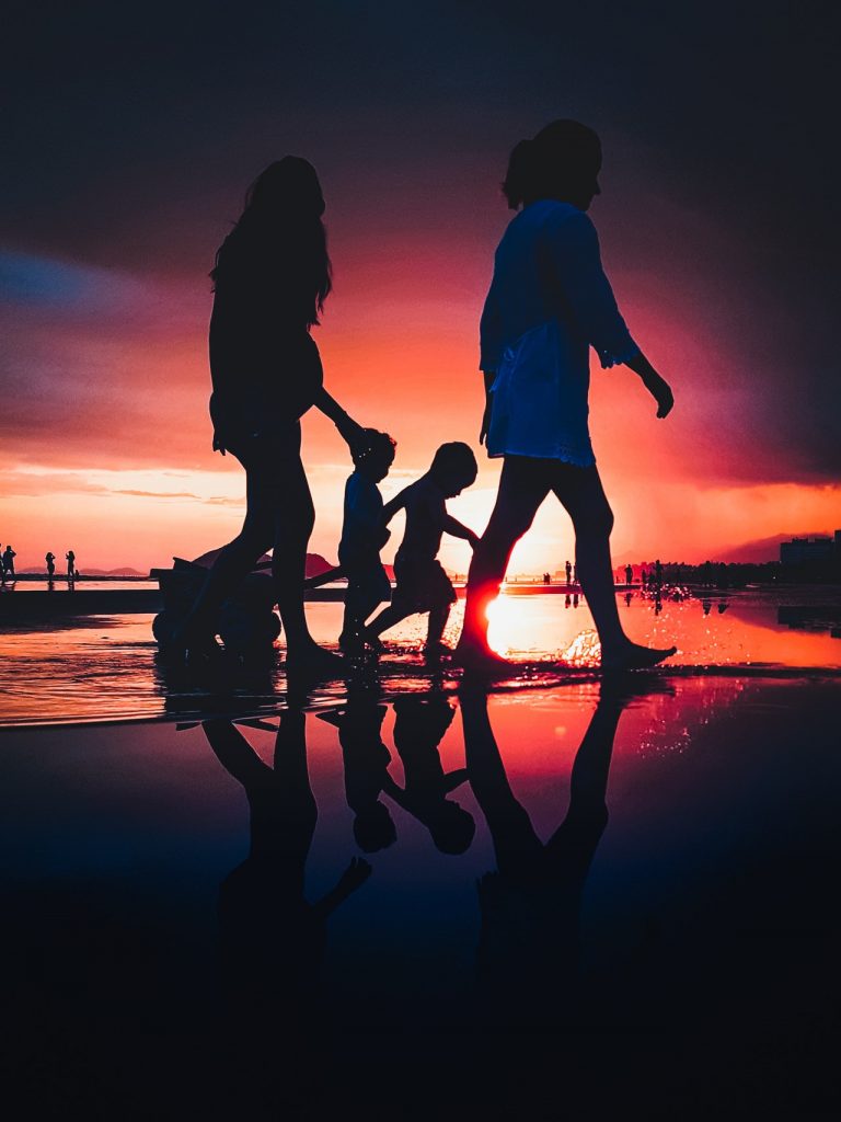 a man and woman holding hands on a beach at sunset