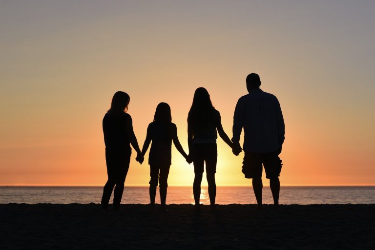 a group of people holding hands and walking on a beach
