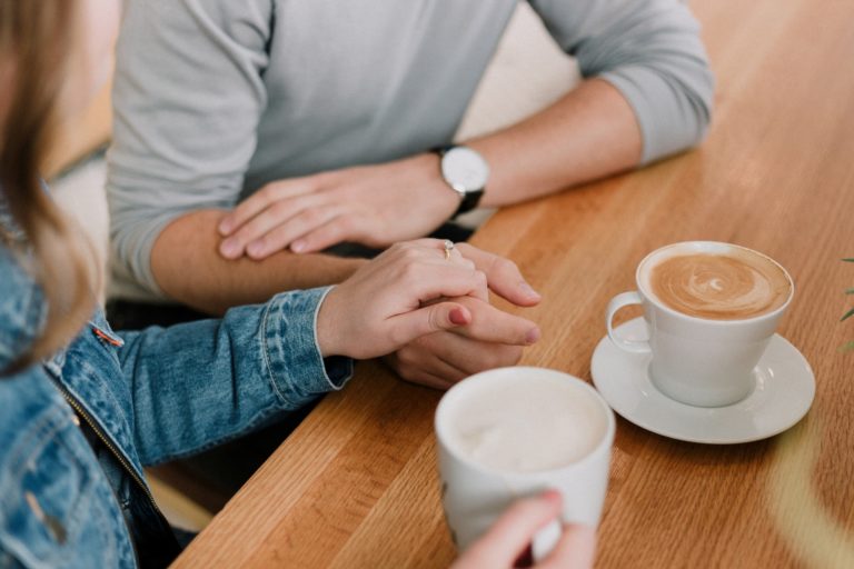 a man and woman sitting at a table with coffee cups