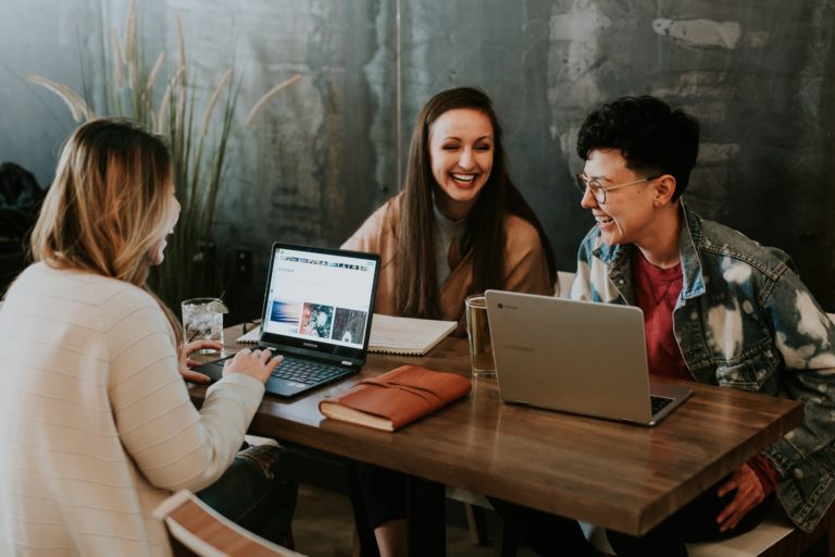 a group of people sitting at a table with laptops