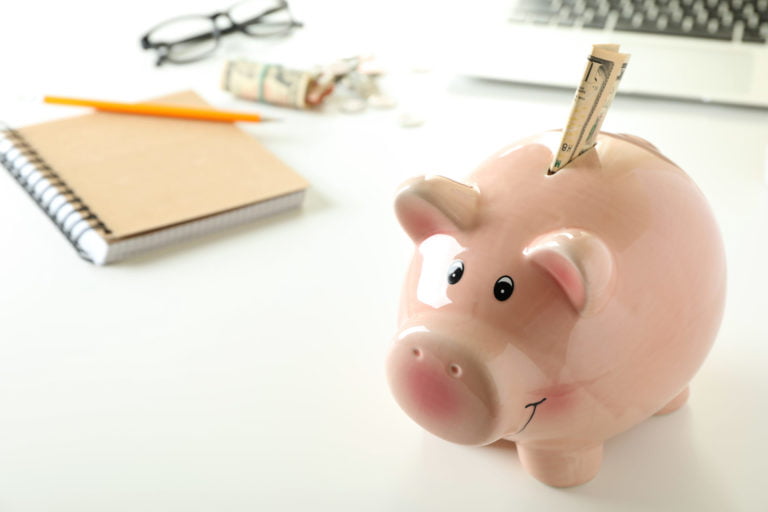 a pink piggy bank with a pen on it
