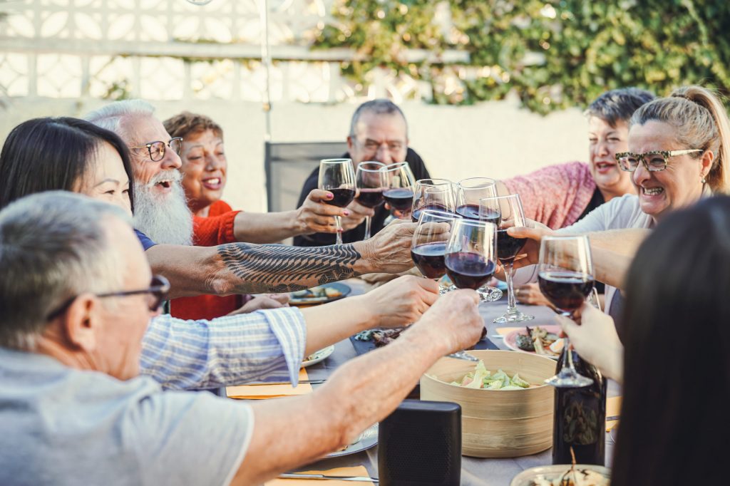 Happy family cheering with red wine at reunion dinner in garden